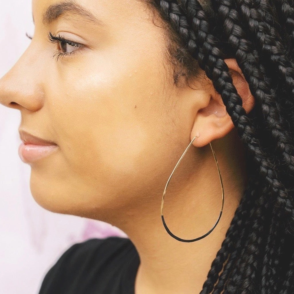 Woman wearing teardrop hoop earrings.
