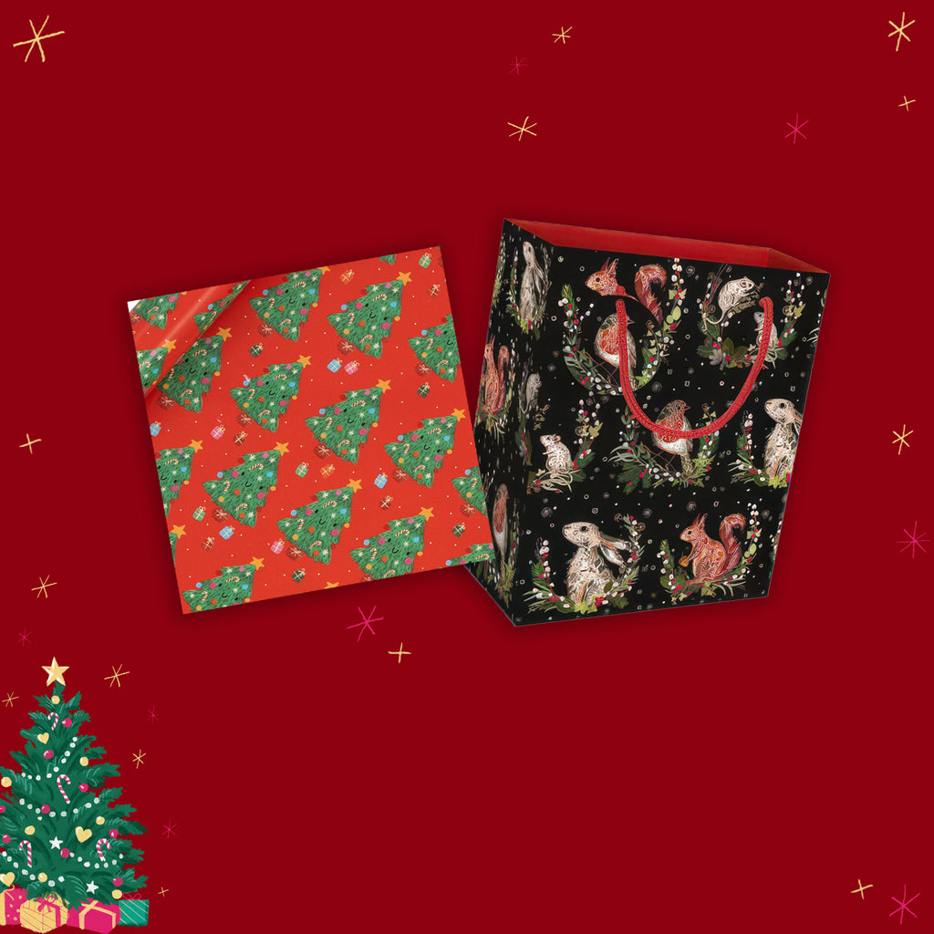 Two gift bags with festive patterns on a red background with Christmas tree decorations.