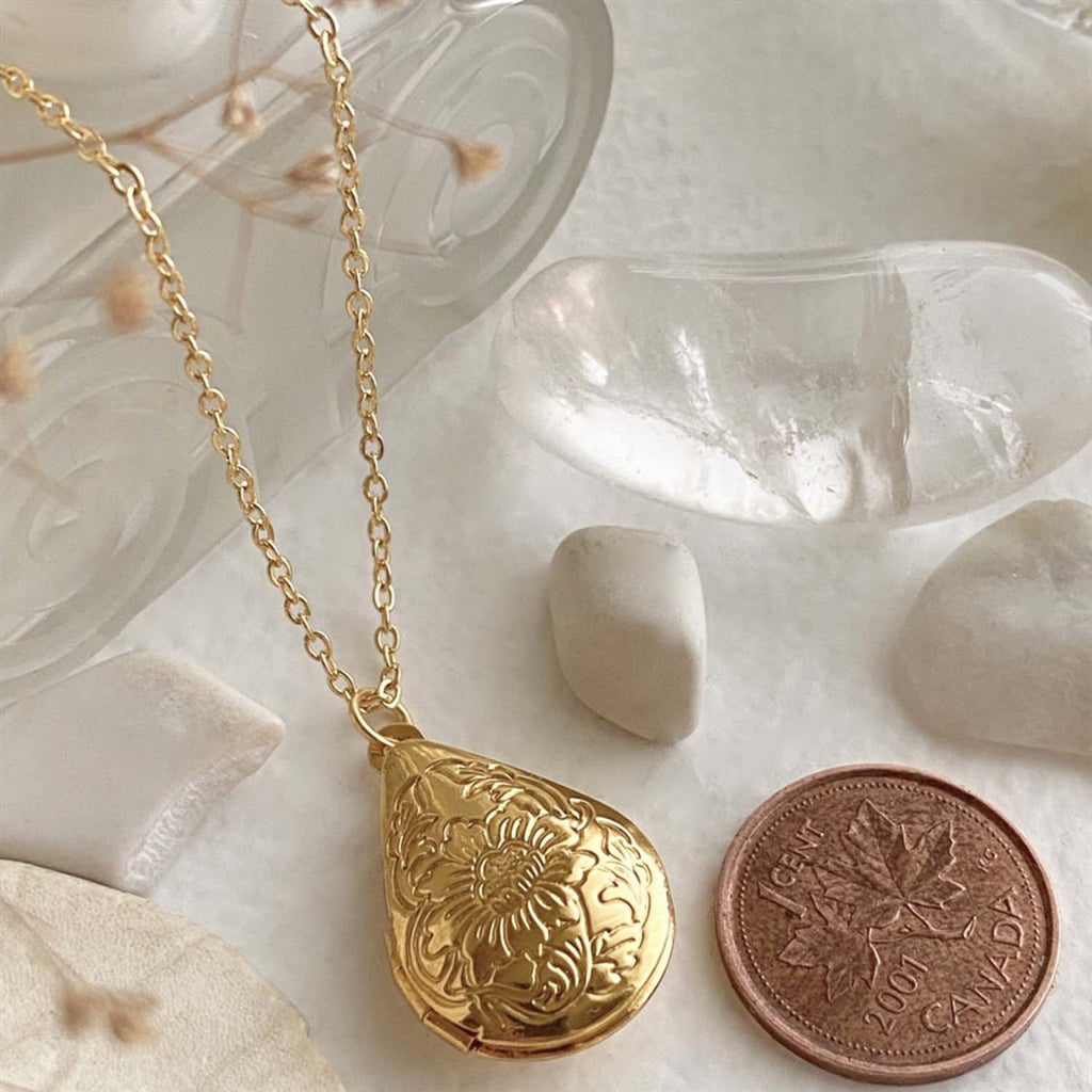 Floral Design Teardrop Locket Necklace Gold besides a penny.