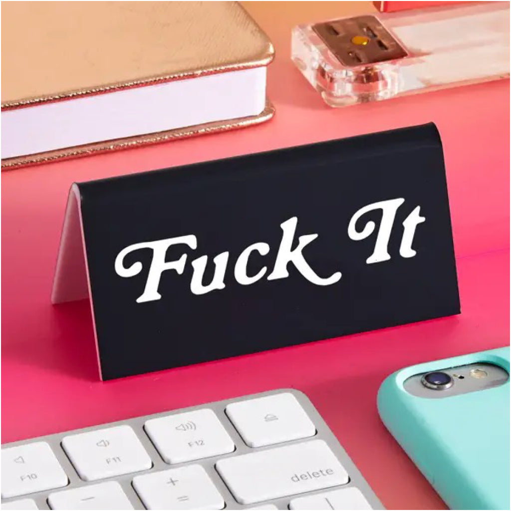 Fuck It Desk Sign on table.