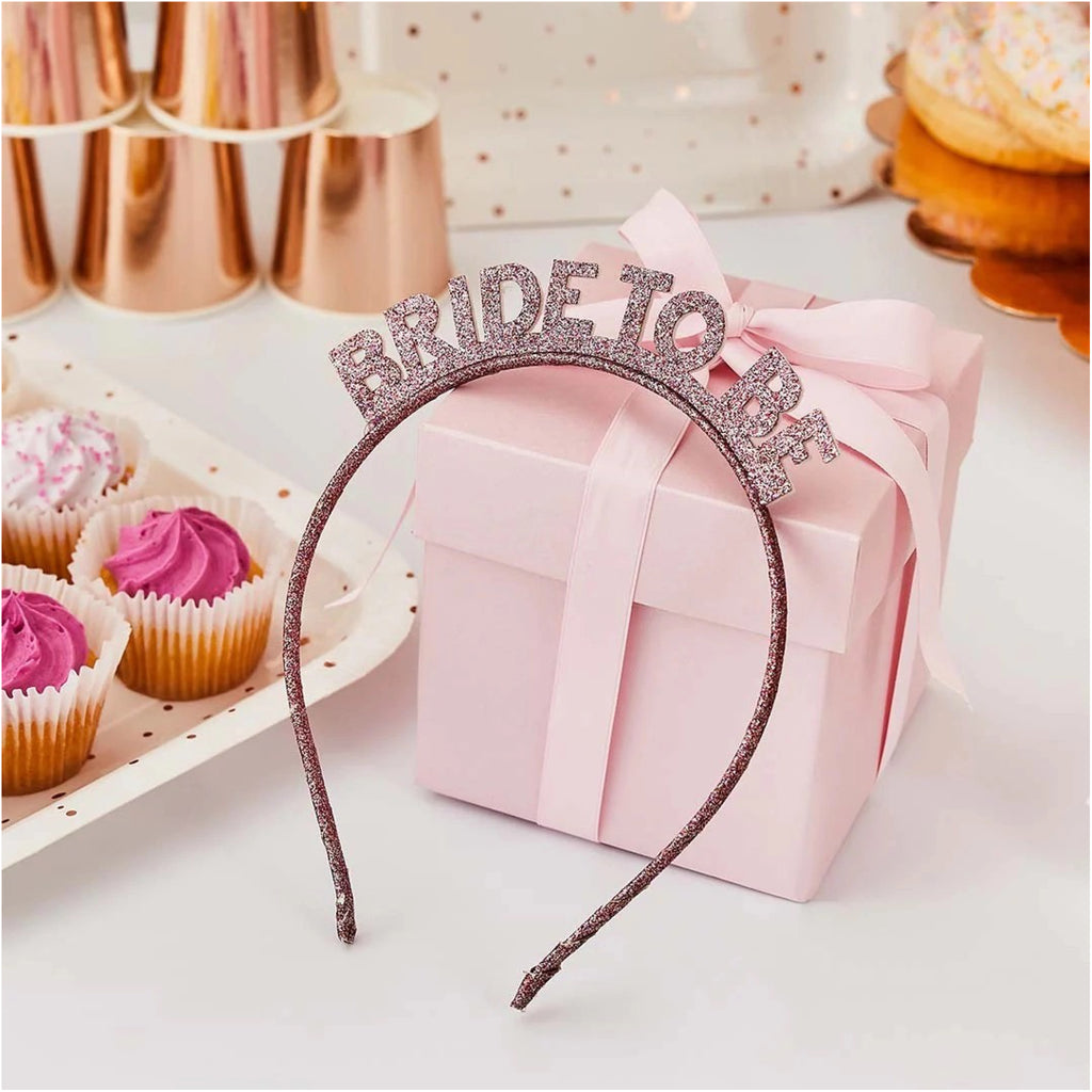 Rose Gold 'Bride To Be' Glitter Headband leaning against presence.