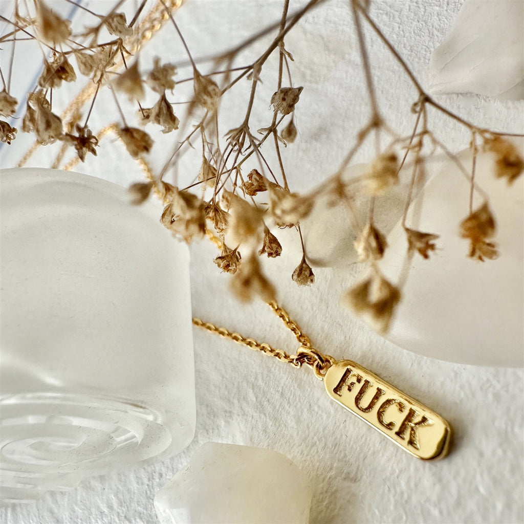 Salty Language Charm Necklace Gold on table.