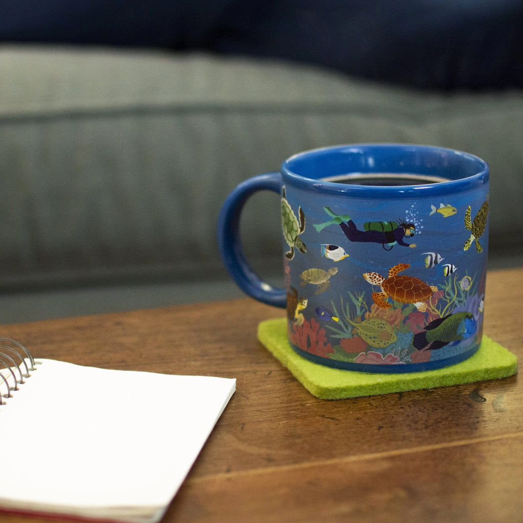 Sea Turtles At The Coral Reef Mug on table.