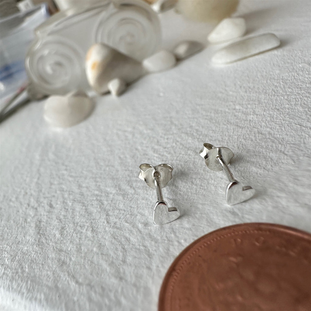 Tiny Heart Stud Earrings Sterling Silver besides a penny.