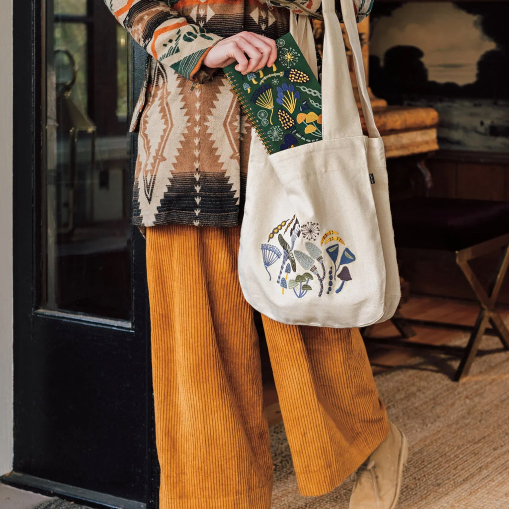 Wildgrove Embroidered Notebook being placed in bag.