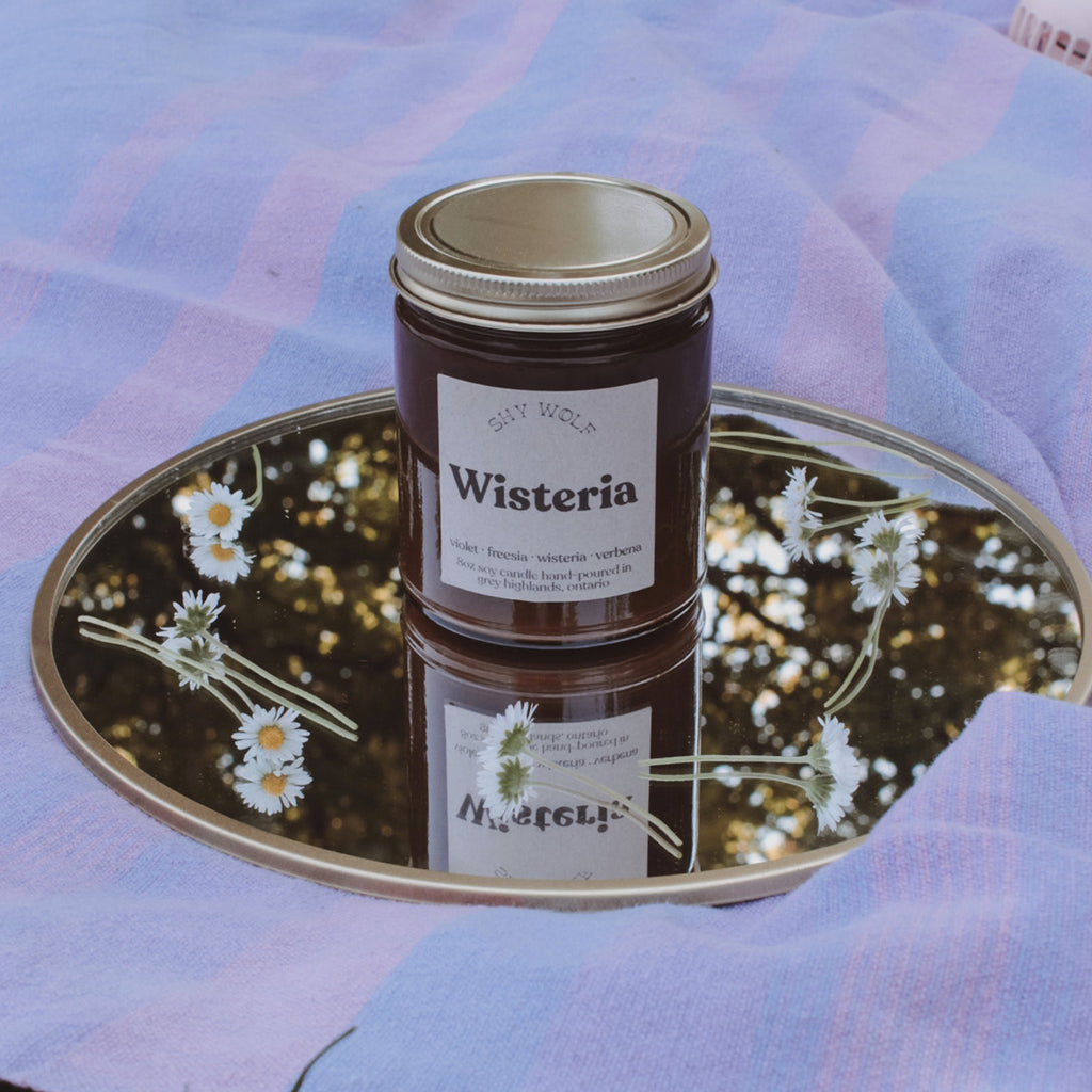 Wisteria Soy Candle on table.