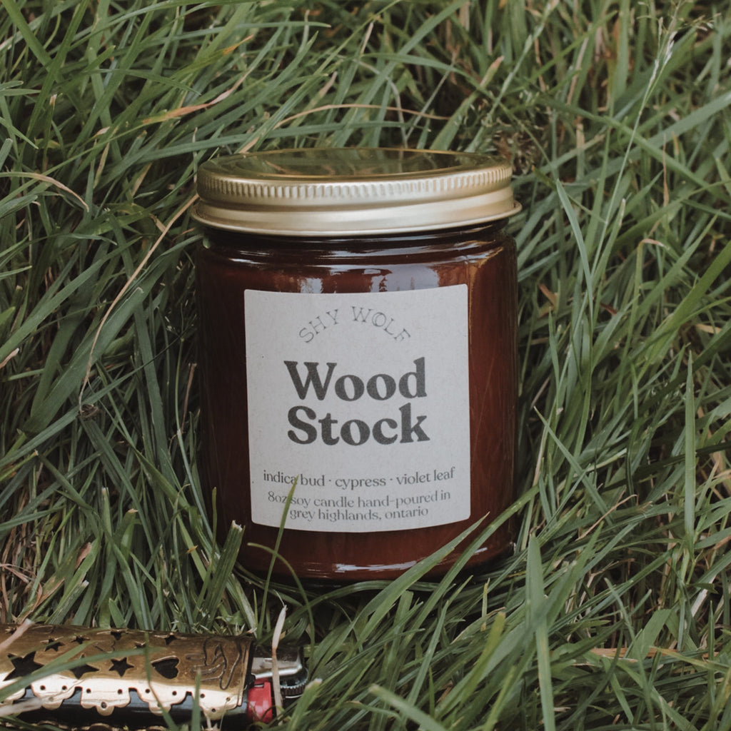 Woodstock Soy Candle on grass.