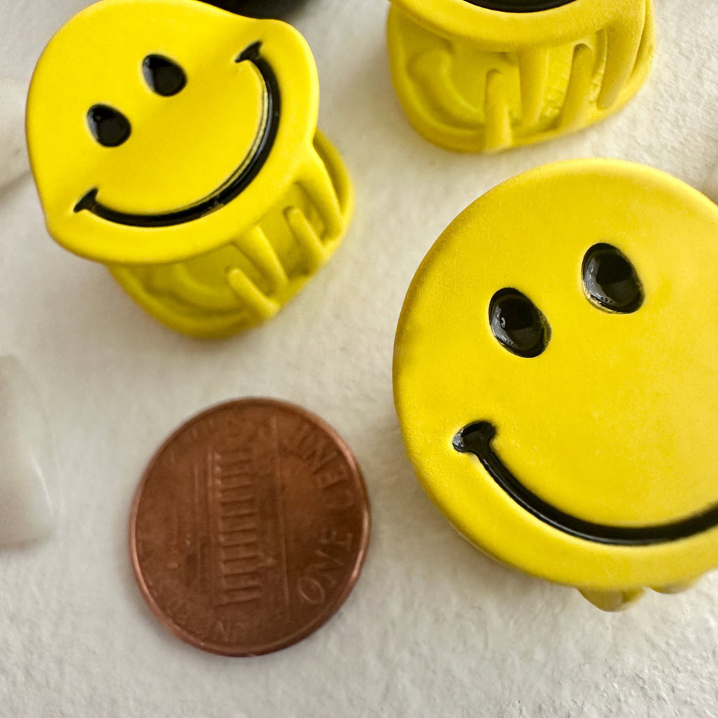 Yellow Mini Happy Face Hair Claw besides a penny.
