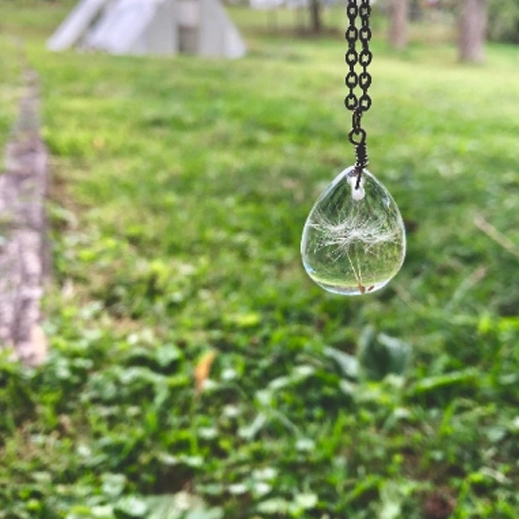Dandelion Seed Necklace Gunmetal in front of grass.