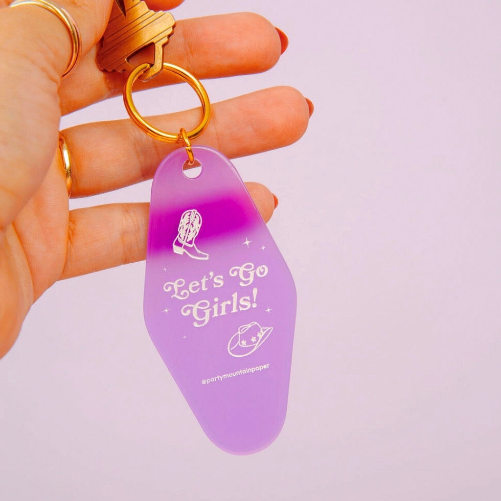 Let's Go Girls Motel Tag Keychain being held.