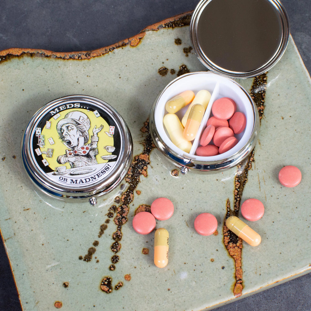 Mad Hatter Pill Box on table.