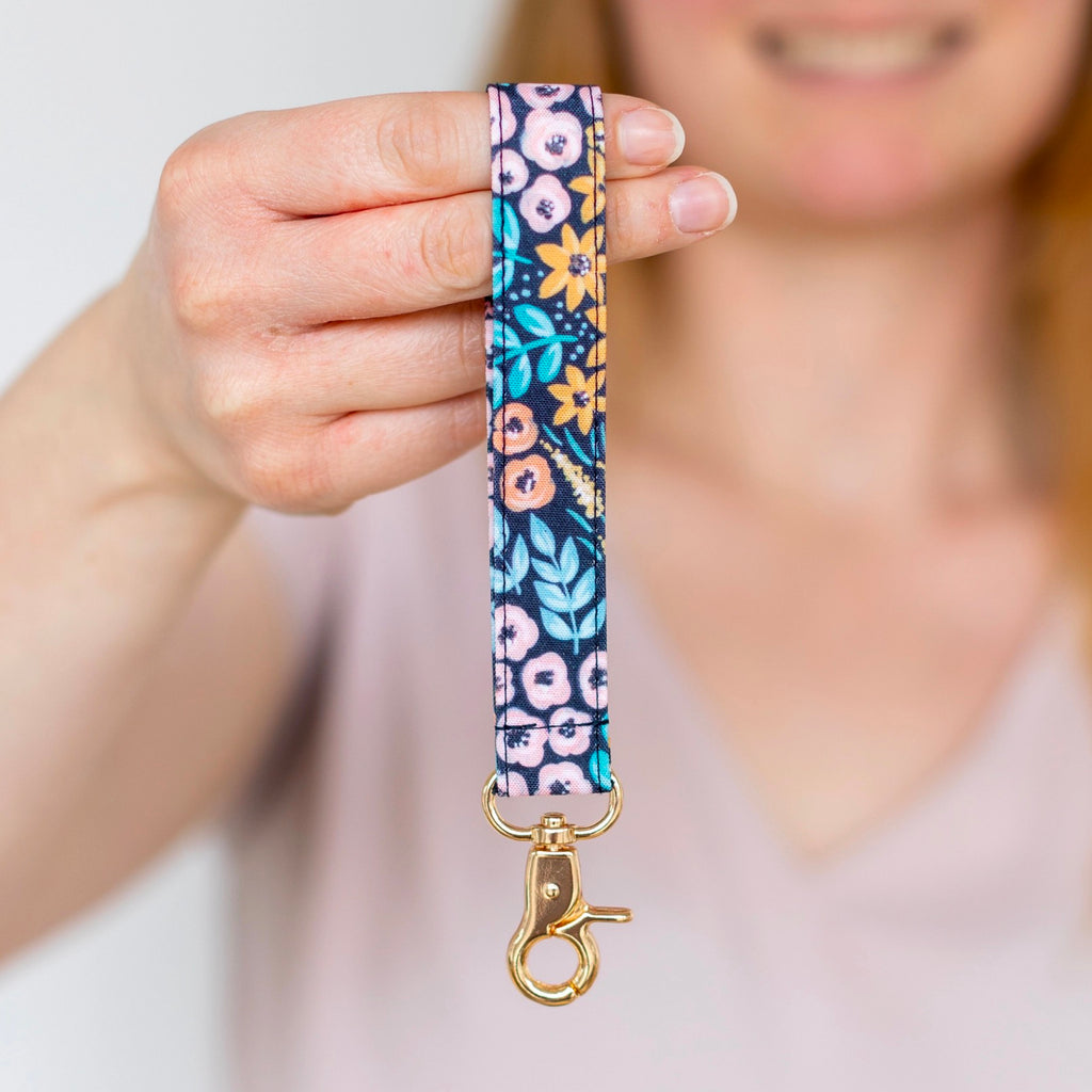Person holding Black Floral Wristlet Keychain.