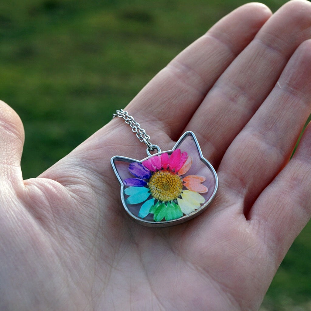 Person holding Rainbow Daisy Cat Necklace.