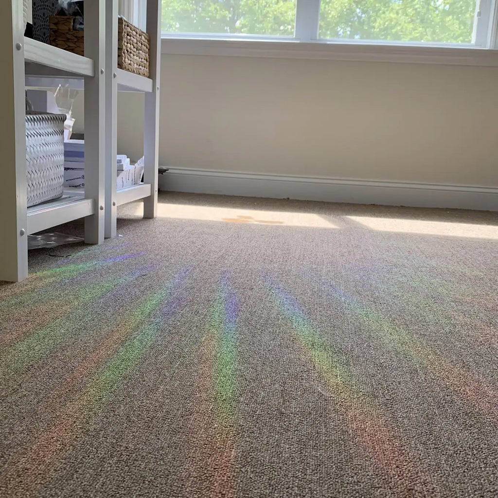 Rainbow Sun Catcher Window Decal light on carpet.