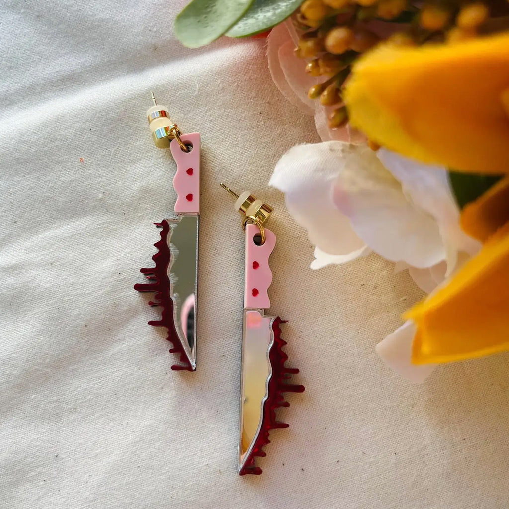 Sweetheart Bloody Knife Earrings on table.