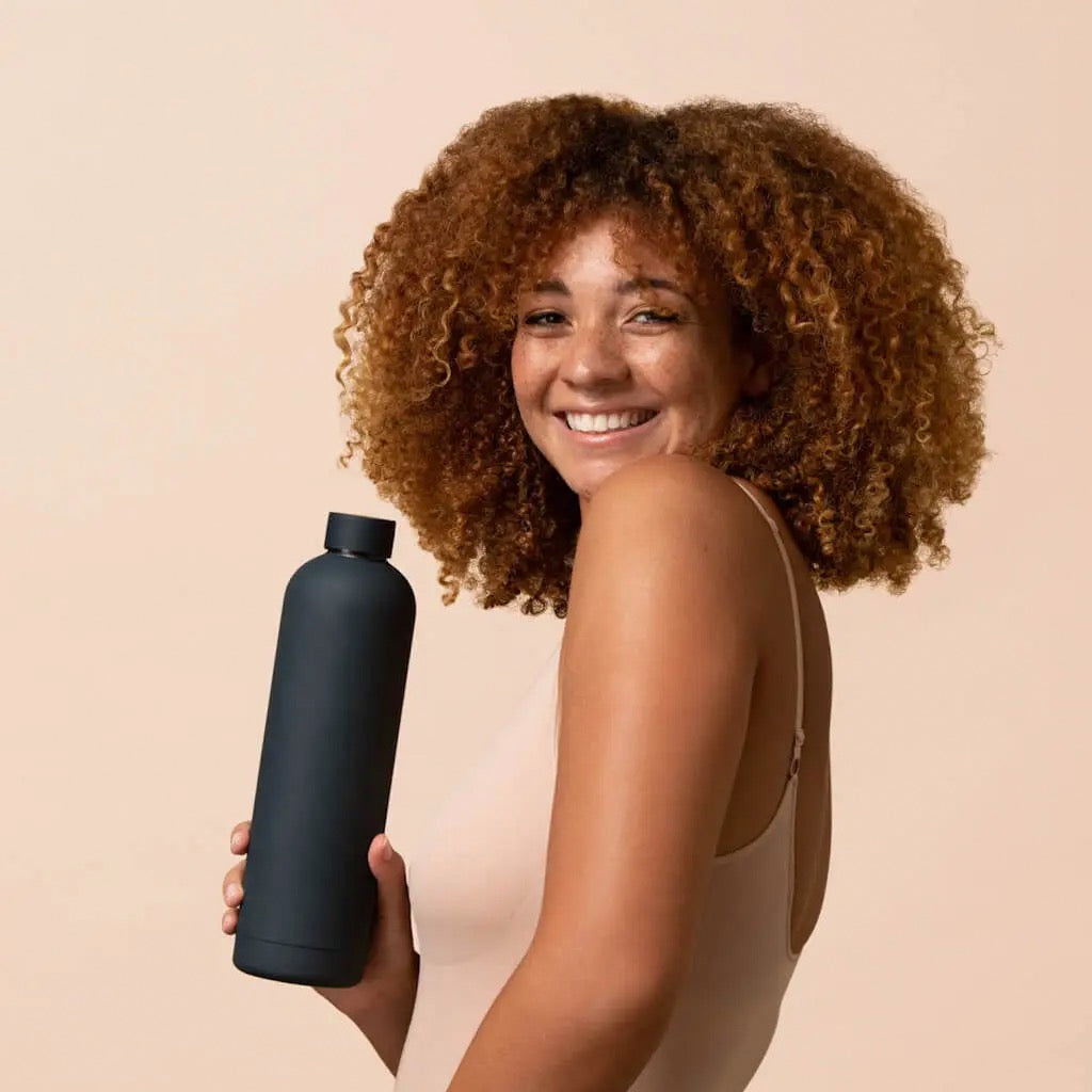 Woman holding 1L black Beysis water bottle.